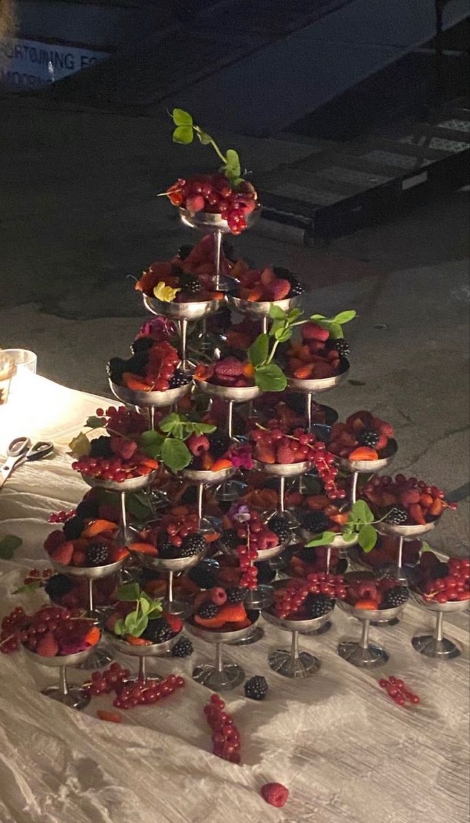 a table topped with lots of desserts and cups filled with berries on top of each other