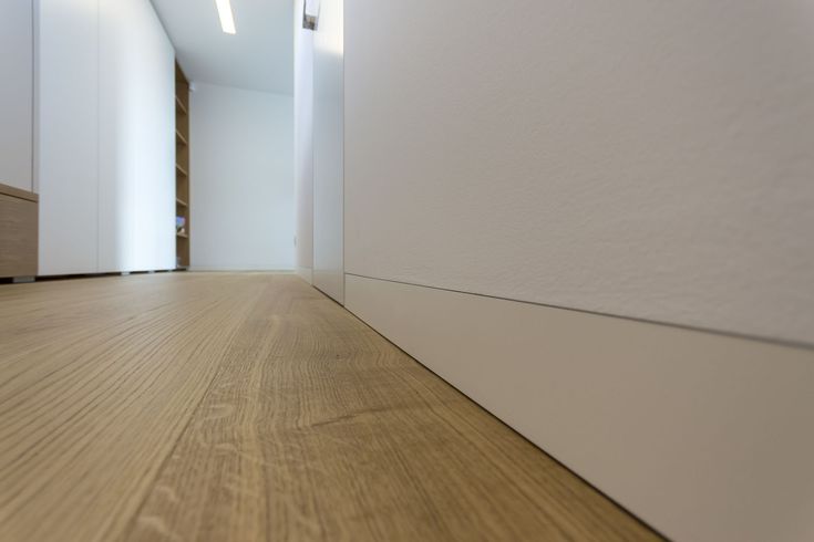 an empty room with wood floors and white walls, in the middle of a hallway