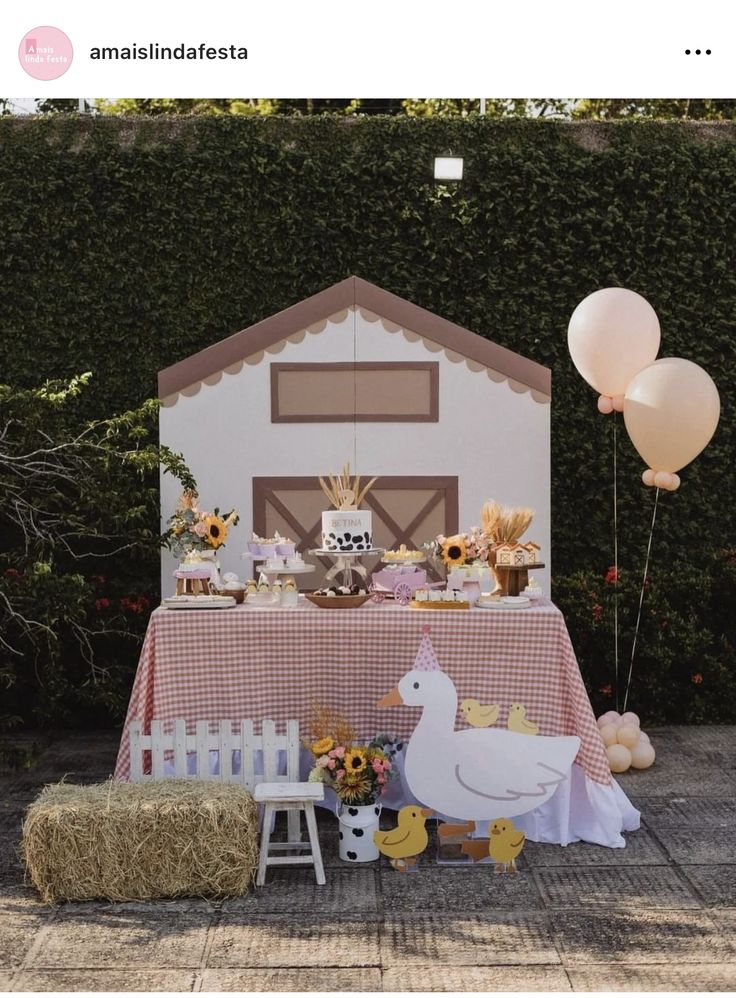 a table set up with farm animals, hay bales and balloons in front of a house