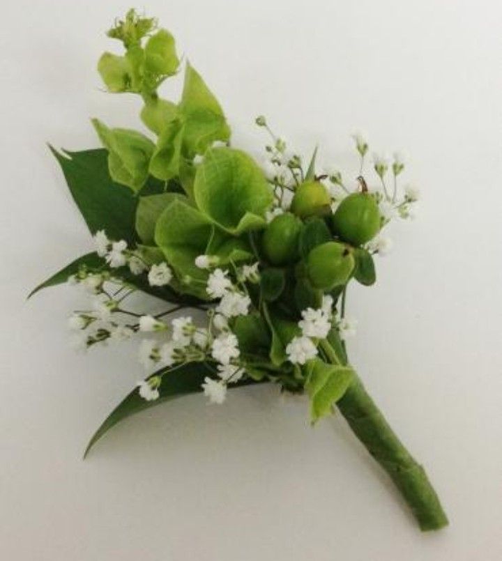 a bouquet of white flowers and green leaves on a white table top with the stems still attached