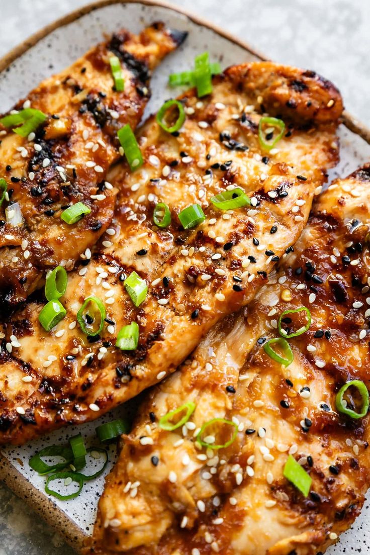 grilled chicken with sesame seeds and green onions on a platter, ready to be eaten