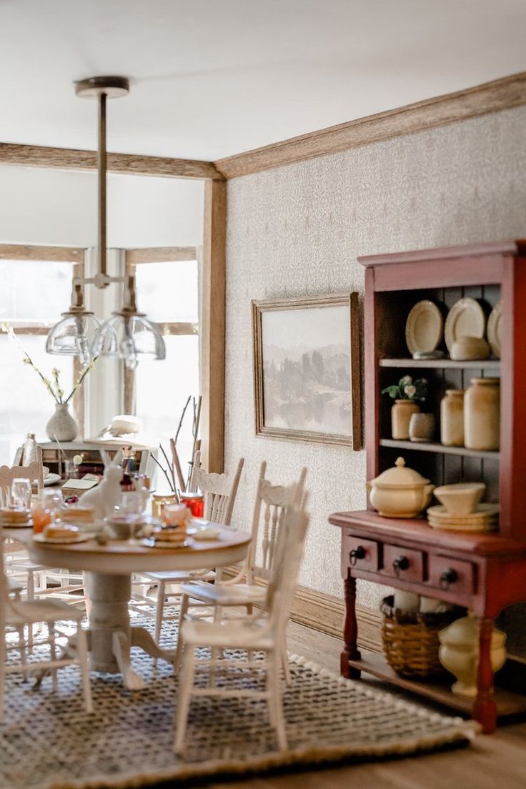 a dining room table and chairs in front of a window with an old china cabinet