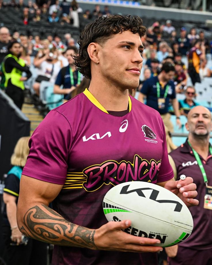 a man holding a rugby ball in front of a crowd