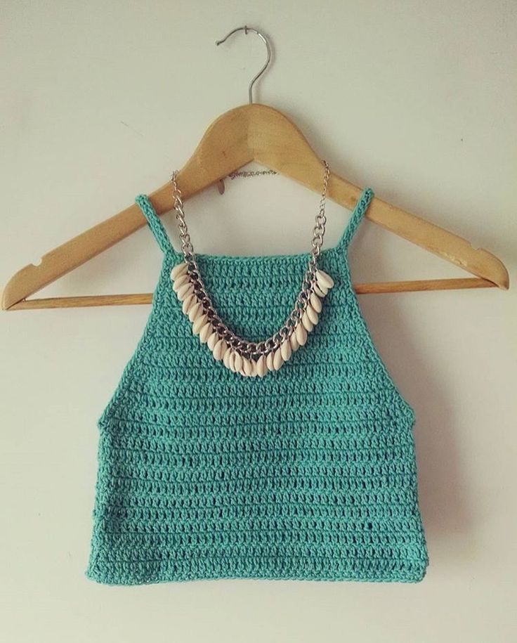 a crocheted top hanging on a wooden hanger