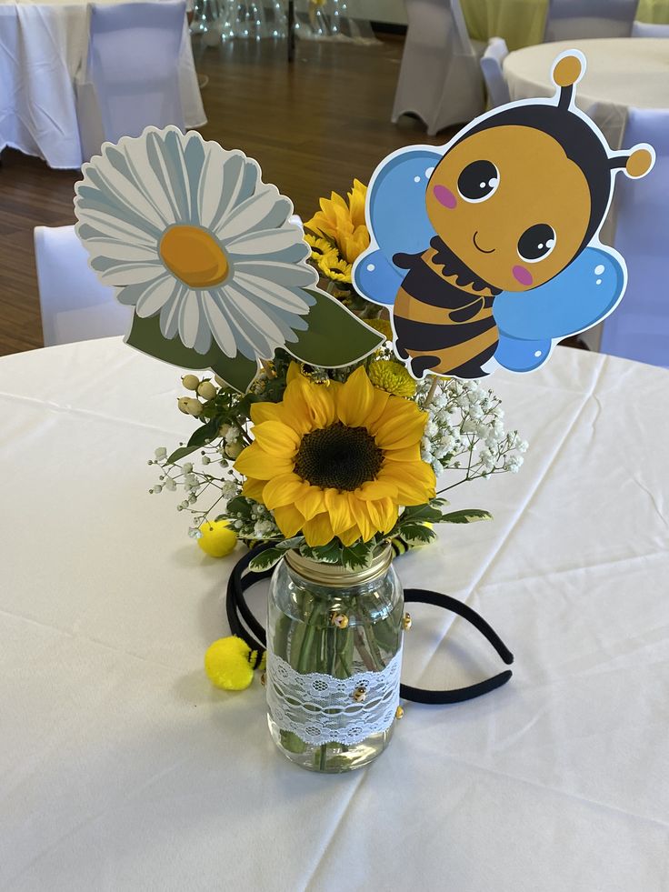 a vase filled with sunflowers and daisies on top of a white table