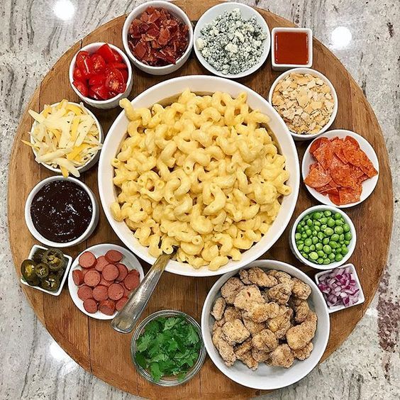 a wooden platter filled with different types of pasta and sauces on top of it