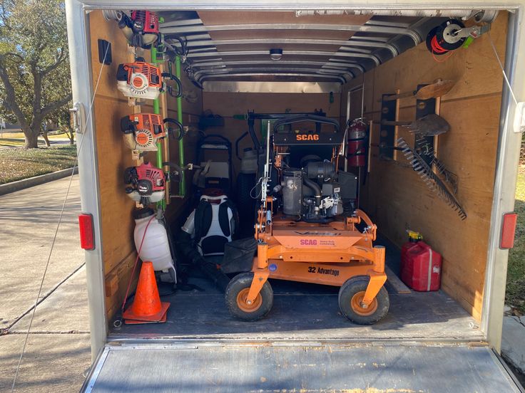 the back end of an enclosed vehicle with tools in it and equipment stored on wheels