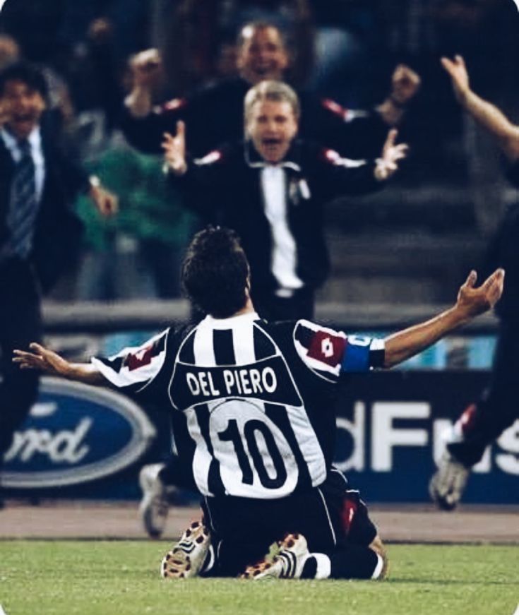 two soccer players sitting on the ground with their arms in the air as they celebrate