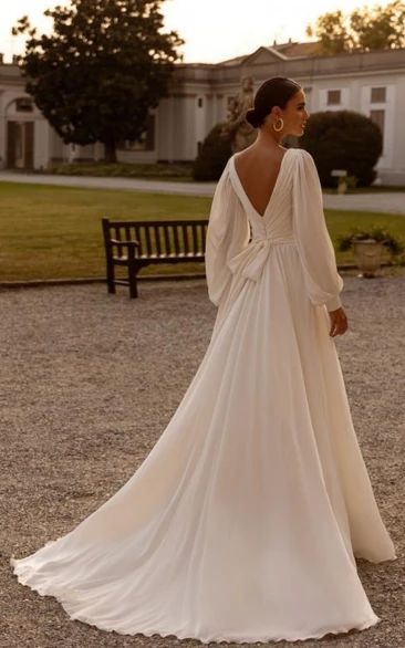 a woman in a white dress is standing on the gravel near a bench and looking off into the distance