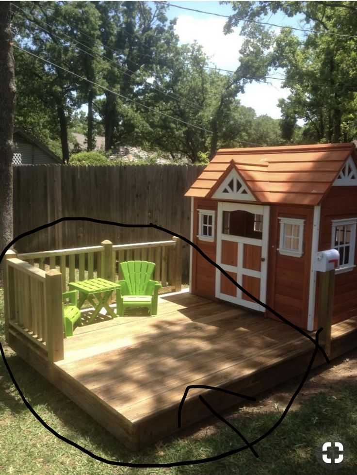 a wooden deck with a little house on it and green lawn chairs in the back