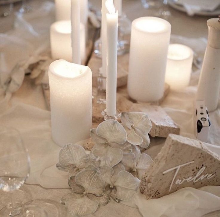 there are many white candles on the table