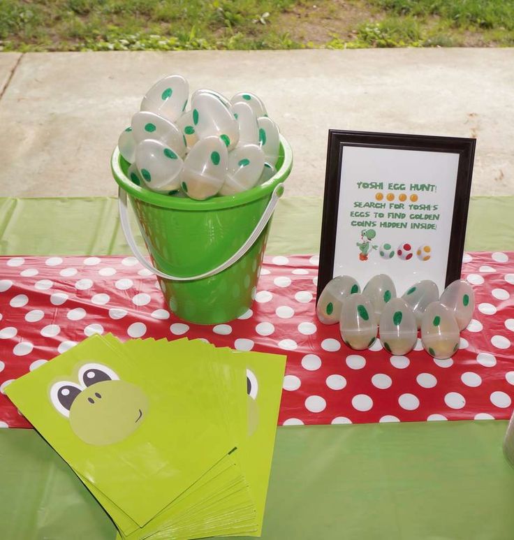 a green bucket filled with white eggs sitting on top of a red and green table