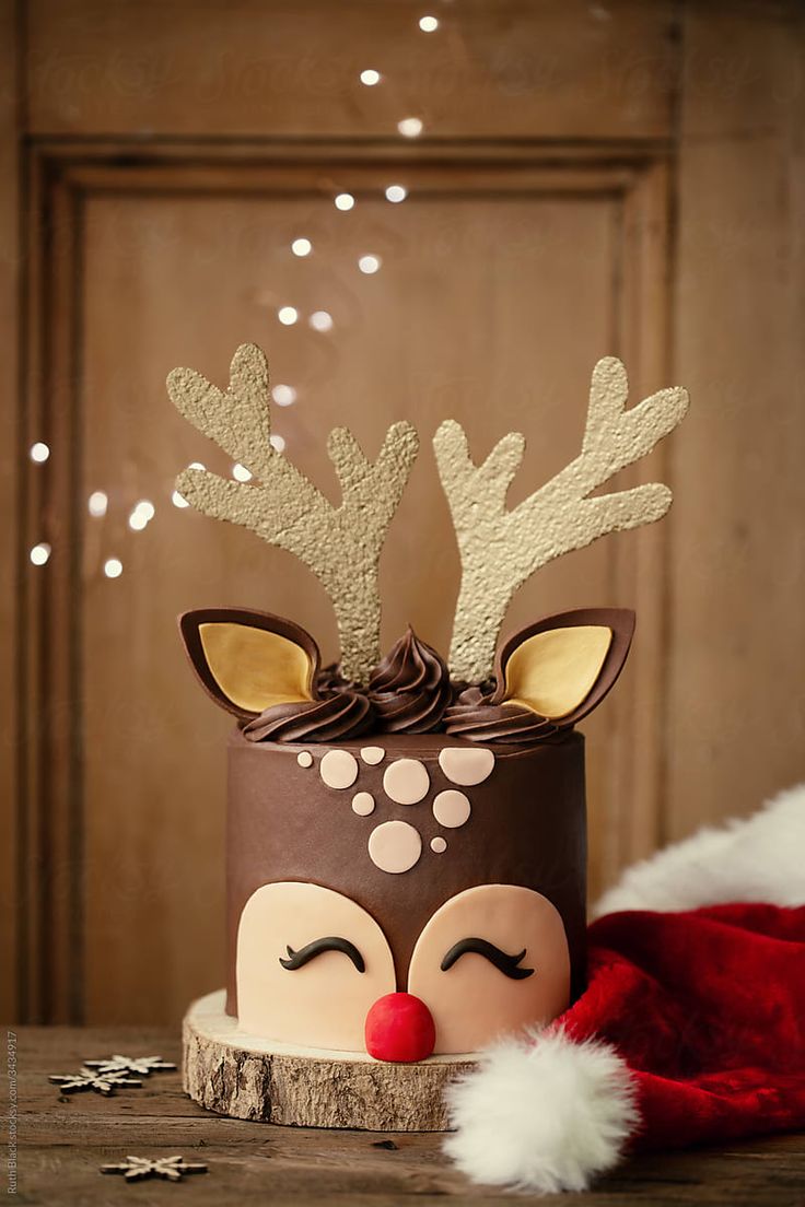 a cake decorated with reindeer's head and nose on top of a wooden table