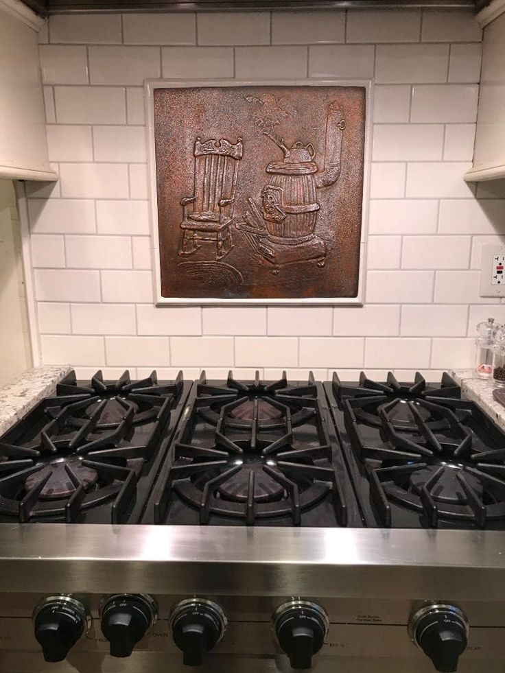 a stove top oven sitting inside of a kitchen next to a painting on the wall