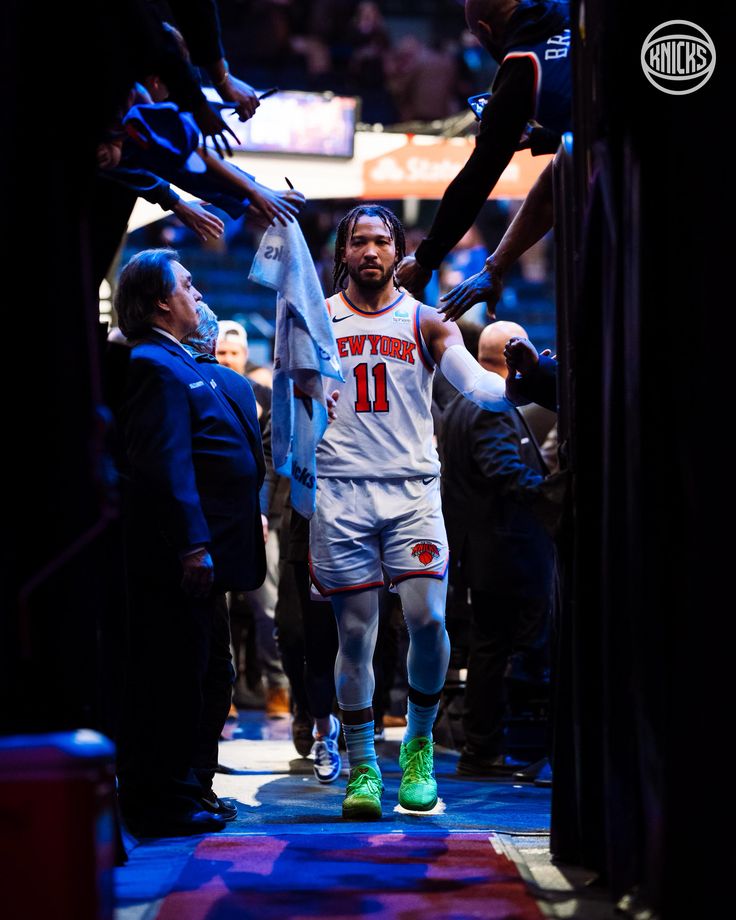 a basketball player is holding up his jersey as he walks down the court with other players