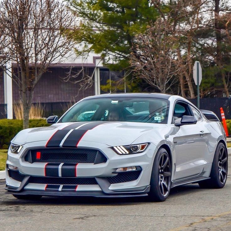 a white car with red and black stripes on it's hood driving down the street