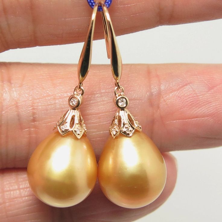 "Lovely in house designed dangle earrings, made of 14k solid yellow gold with 14 natural mine small accent diamonds & a natural GOLDEN, south sea cultured pearls from Australia. Each of the large 'Find Drop' pearl exhibits excellent high luster and thicker nacre. The pearls also possesses a silky smooth surface with just a minimal natural spots/blemish. Style: Hook. Metal Purity: 14k Solid Yellow Gold. Genuine Diamond: 14 pcs / 0.059 ctw. Earring approx. Length (including pearl): 1.4 inches Luxury Gold Pear-shaped Diamond Earrings, Gold Pear-shaped Diamond Earrings With Accents, Exquisite Gold Dangle Diamond Earrings, Gold Teardrop Diamond Earrings Hallmarked, Gold Hallmarked Teardrop Diamond Earrings, Gold Pear-shaped Earrings With Diamond Accents, Gold Teardrop Hallmarked Diamond Earrings, Gold Pear-shaped Diamond Earrings, Pear-shaped Yellow Gold Earrings With Diamond Accents