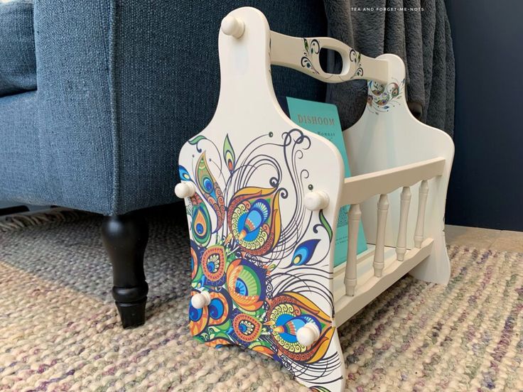 a baby crib with a colorful design on the front and sides, next to a blue couch