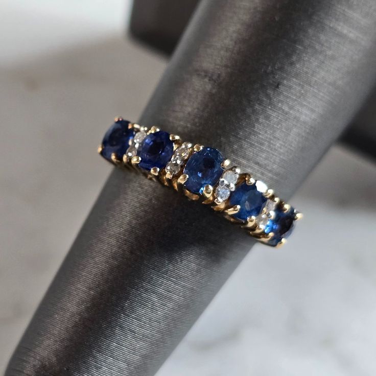 a gold ring with blue and white stones sits on top of a piece of cloth