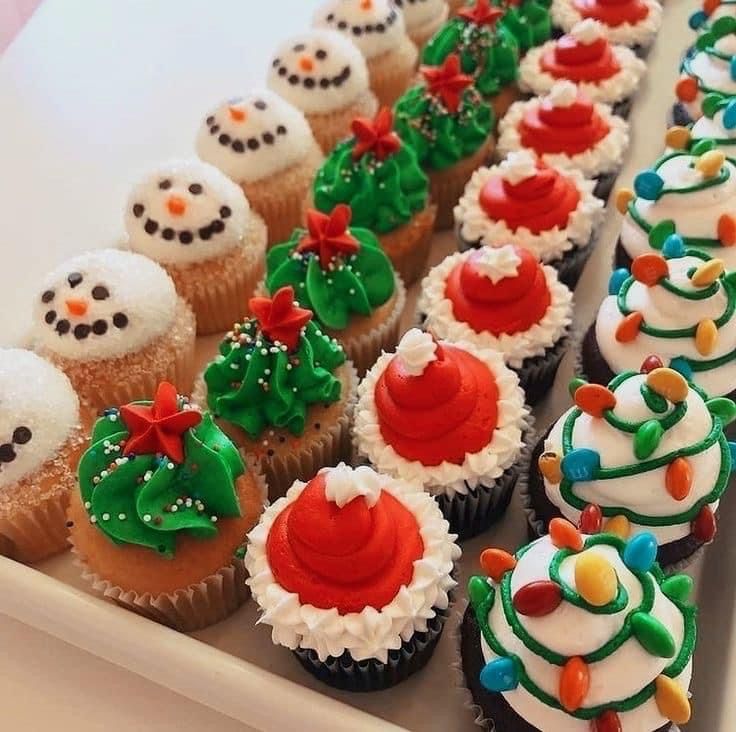 cupcakes with frosting and decorations are lined up on a tray