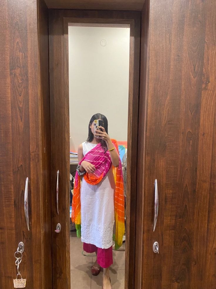 a woman taking a selfie in front of two wooden doors with the door open