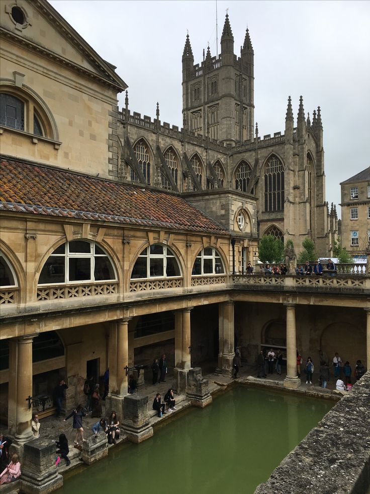 people are walking around in an old building next to a river with water running through it