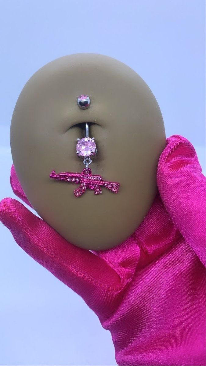 a doll's hand holding a dummy with a pink bow tie and jeweled nose ring