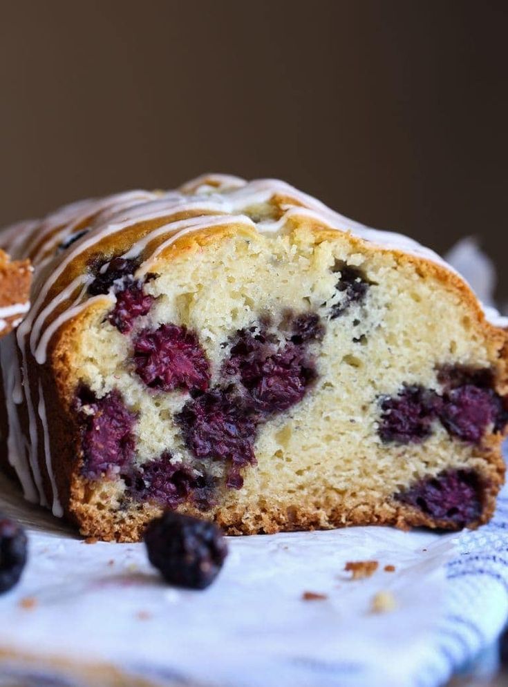 a loaf of blueberry pound cake on a plate with fresh berries and icing