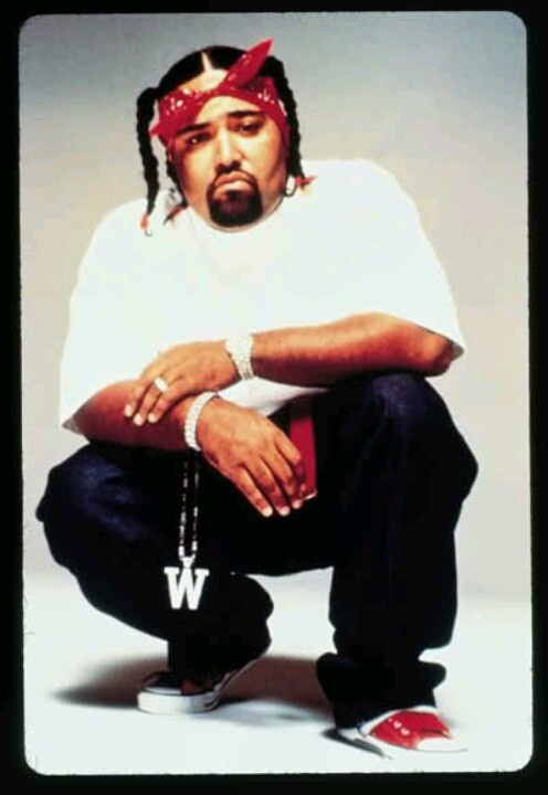 a man in white shirt and red bandanna sitting on top of a fire hydrant