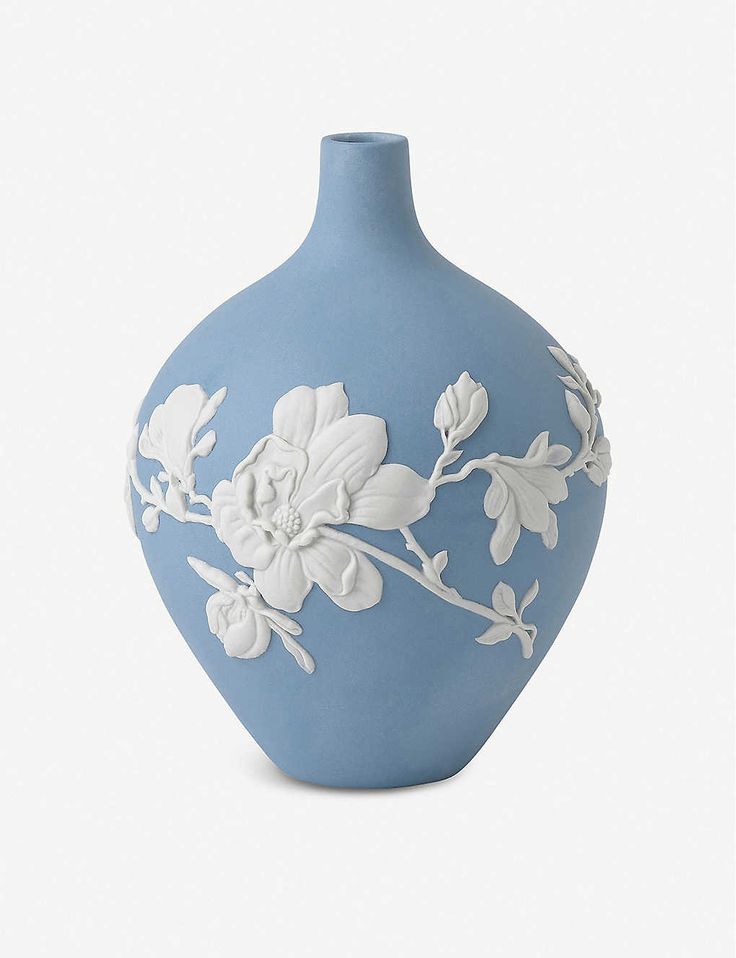 a blue vase with white flowers painted on the front and sides, sitting on a white surface