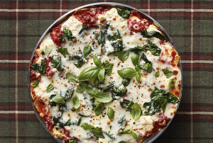 a pizza sitting on top of a pan covered in cheese and spinach