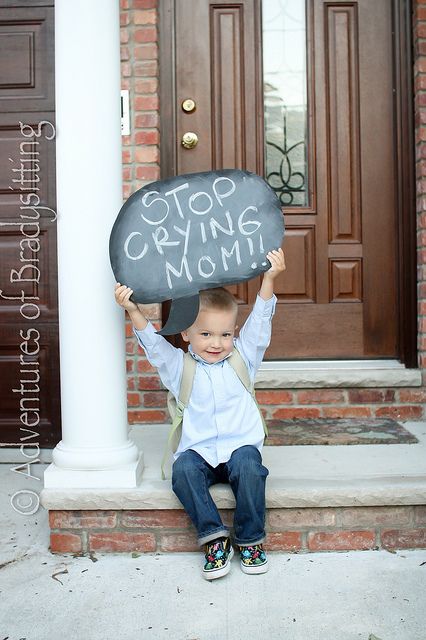 a little boy sitting on the steps holding up a sign