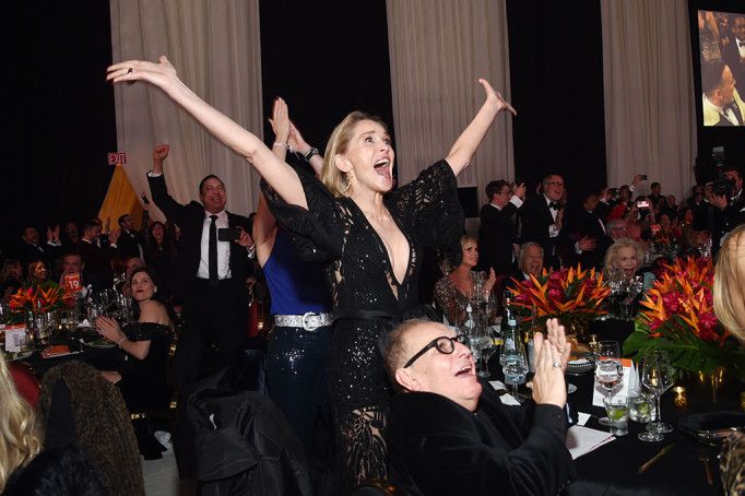 a woman in a black dress standing on top of a table next to a man