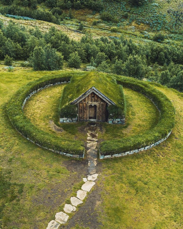 an aerial view of a house in the middle of a field with grass growing on it