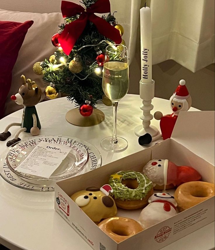 a box filled with doughnuts sitting on top of a table next to a christmas tree