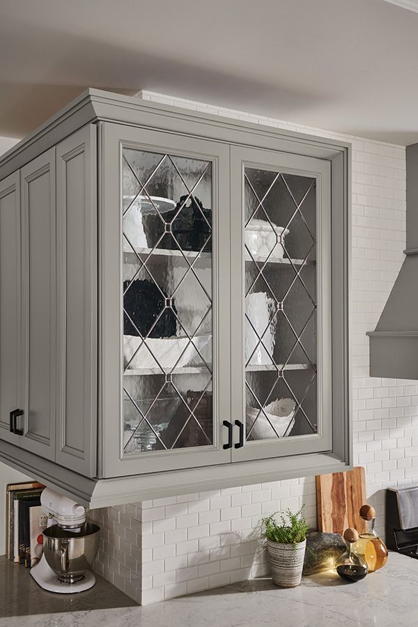 a gray cabinet with glass doors in a kitchen next to a stove and counter top