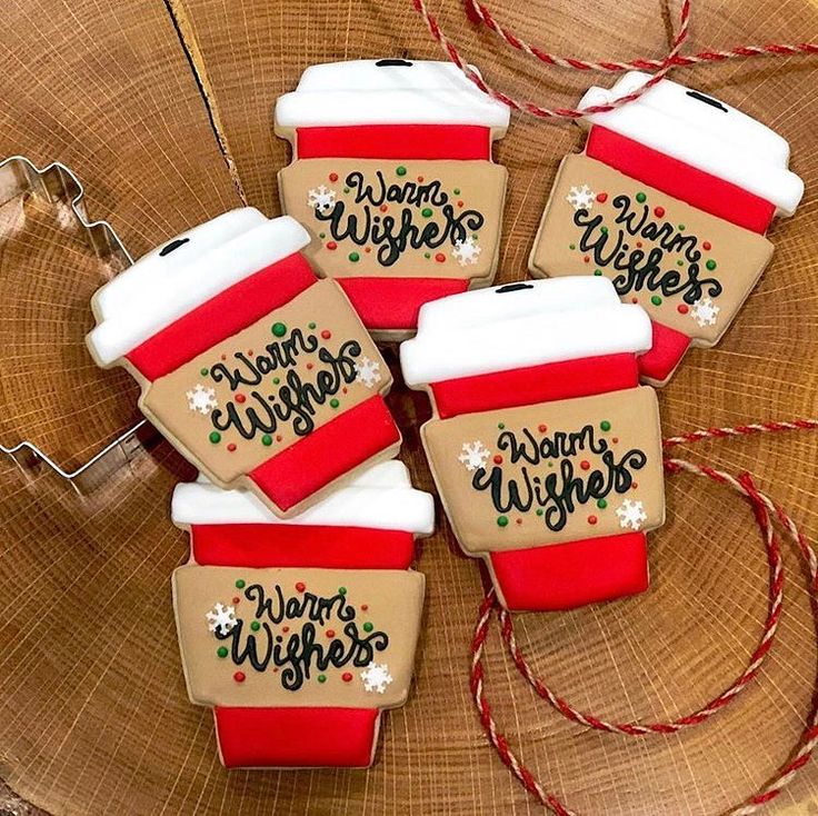 four decorated cookies sitting on top of a wooden table next to twinkies with writing on them