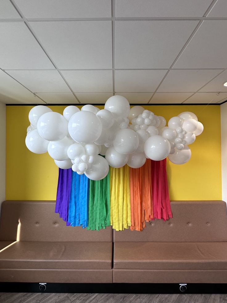 White balloon cloud with rainbow tassels coming our of the bottom installed on a yellow wall above a brown couch Rainbow Balloon Garland, Floral Balloon Arch, Cloud Garland, Balloon Cloud, Balloon Clouds, Floral Balloons, Balloon Display, Balloon Delivery, Rainbow Balloons