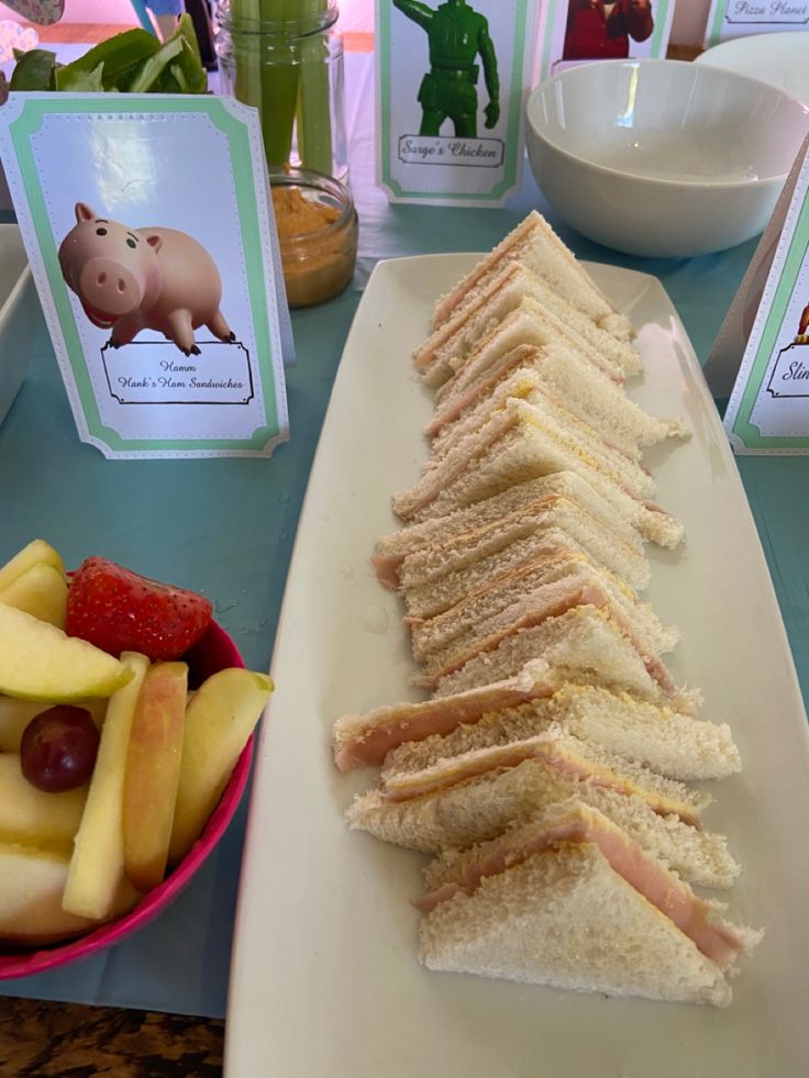 sandwiches and fruit on a table at a children's birthday party with place cards