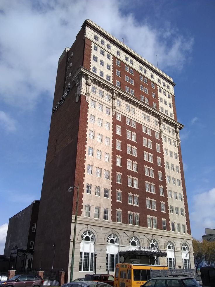 a tall brick building sitting next to a parking lot filled with lots of parked cars