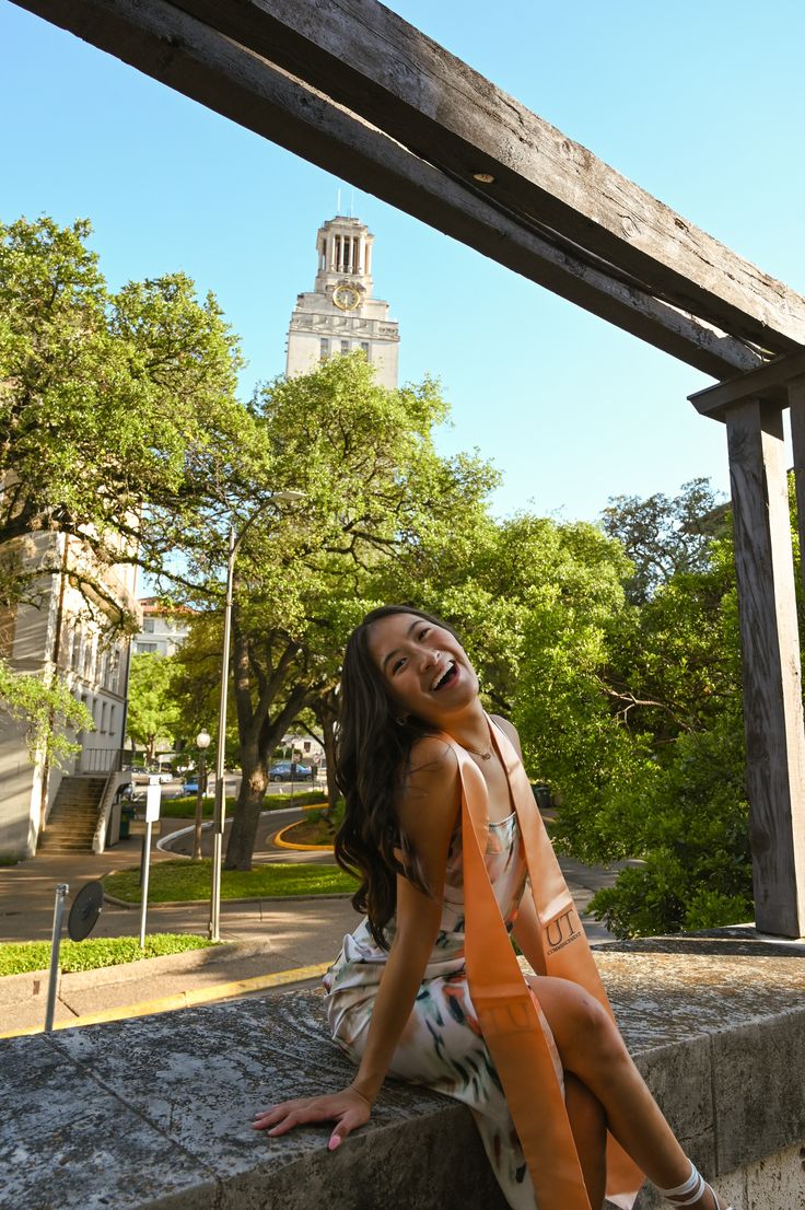 a woman is sitting on a ledge and smiling