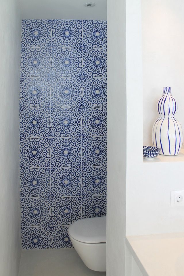 a white toilet sitting next to a blue and white wall