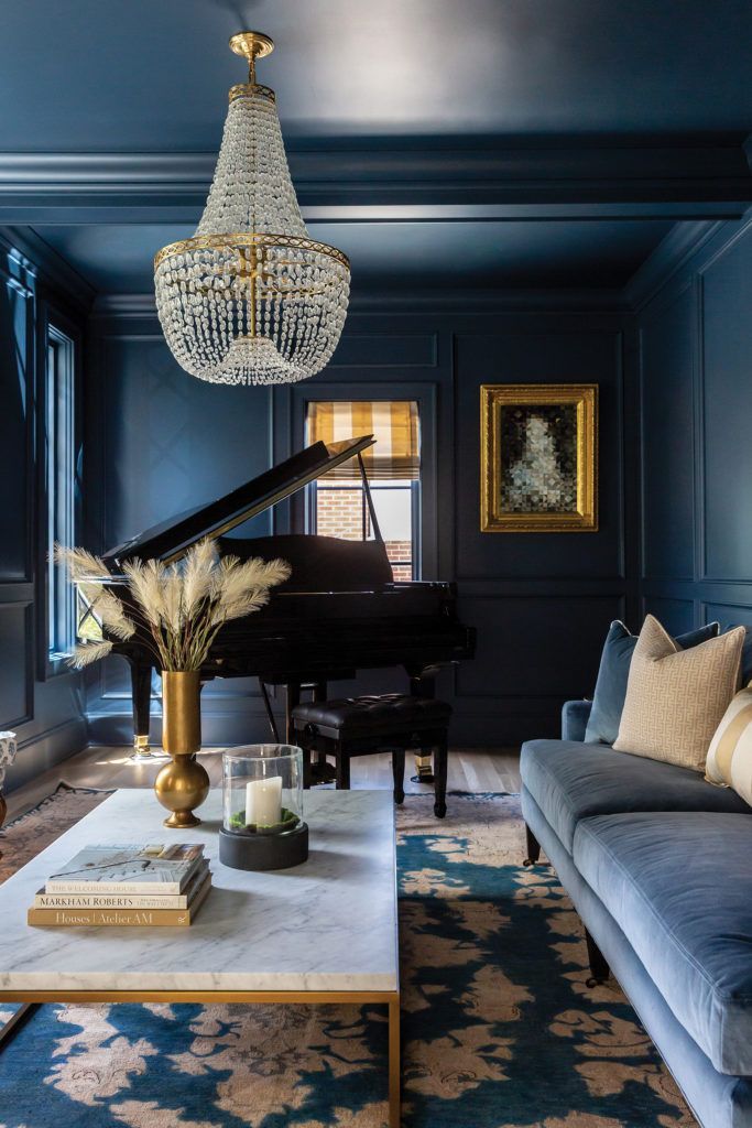 a living room filled with furniture and a chandelier hanging from the ceiling over a piano