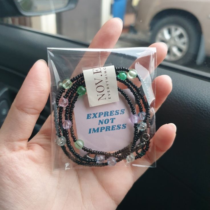 a person holding up a bracelet with beads and charms on it that says express not impress