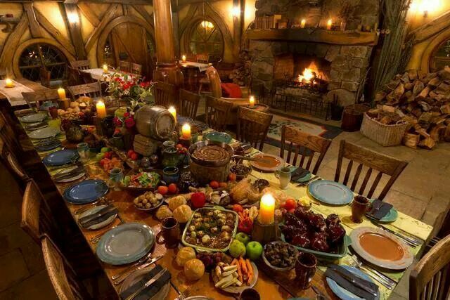 a large table with many plates and bowls on it in front of a fire place