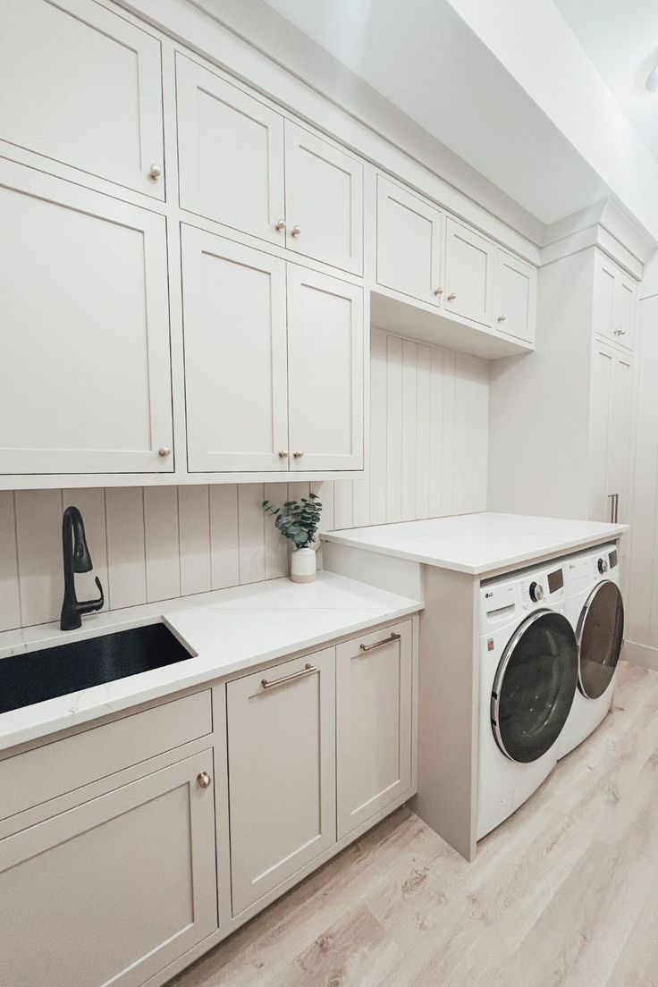 a kitchen with white cabinets and a washer and dryer in the middle of it