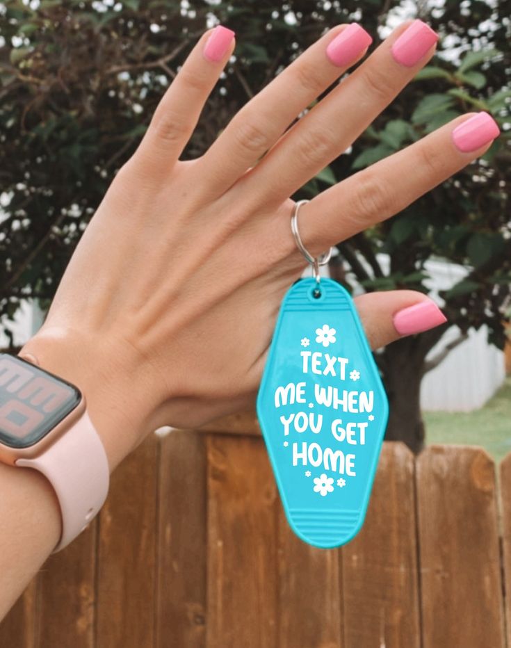 a woman's hand holding a blue tag that says text me when you get home