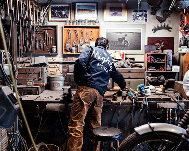 a man working in a shop with lots of tools on the table and bikes parked up against the wall