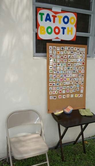 a small table and chair in front of a sign that says tattoo booth on it