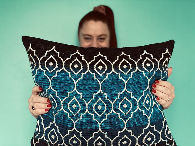 a woman holding a blue and white pillow in front of her face